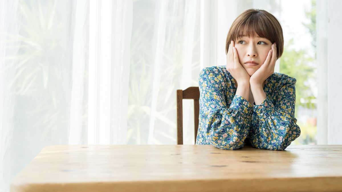 不安そうに頬杖をつく女性