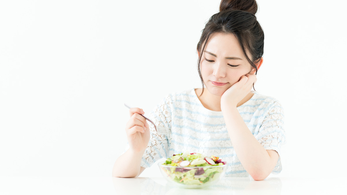 サラダを食べている不満そうな女性
